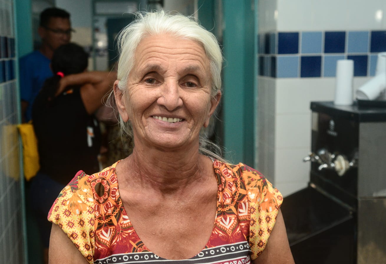 Profissional de saúde realizando atendimento odontológico em uma paciente sentada na cadeira.